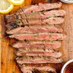 Flank steak that was marinated before grilling sliced against the grain on a cutting board.