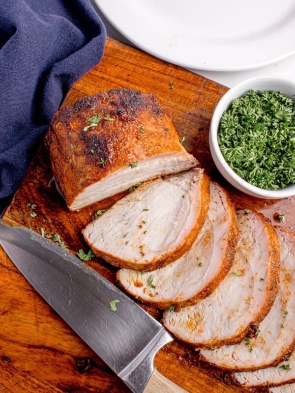 Grilled pork loin sliced on a wooden cutting board. Slices are fanned out to show interior texture.