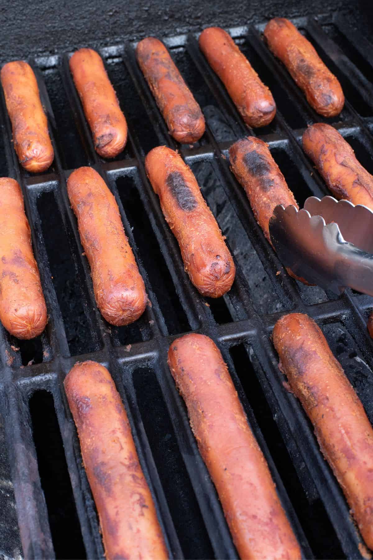 Hot dogs cooking on the grill.
