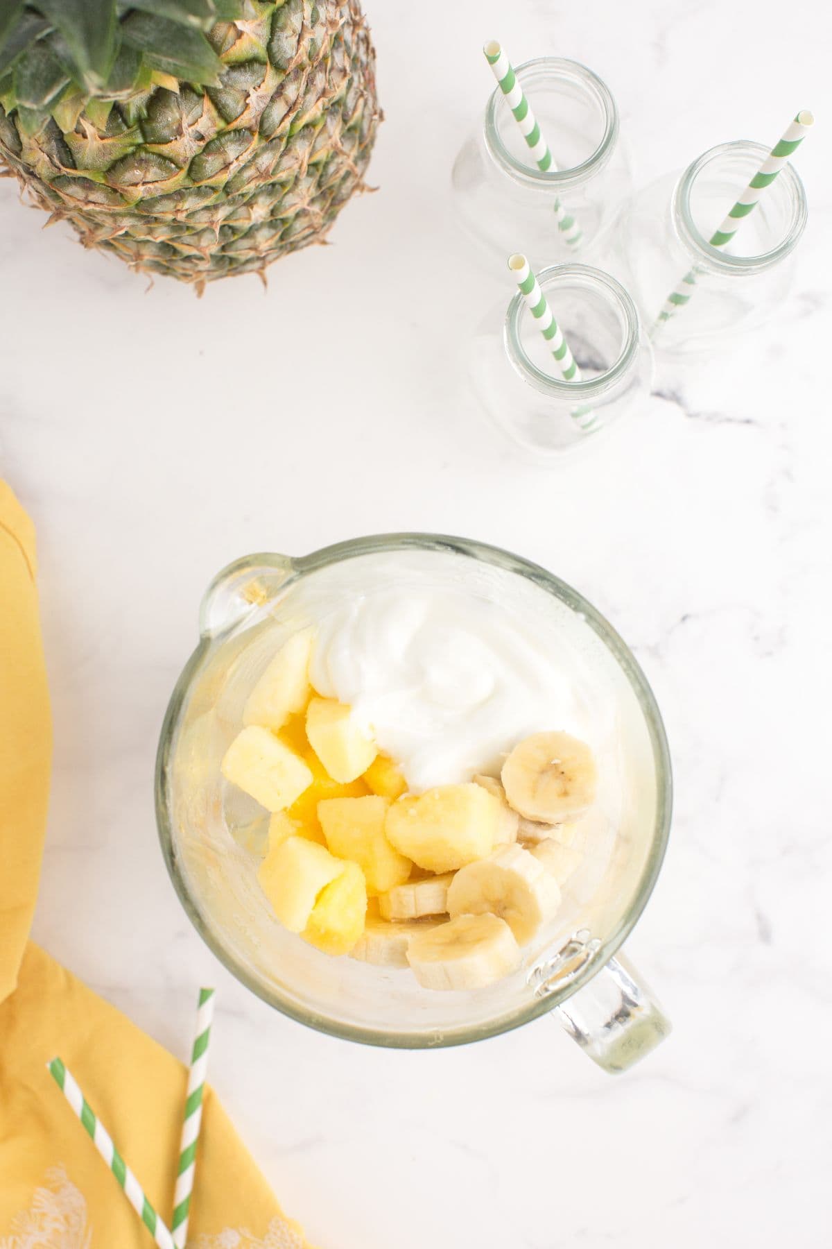 Pineapple smoothie ingredients layered in the glass blender canister.