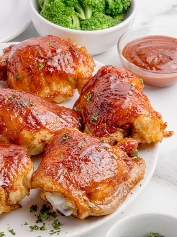 Completed BBQ chicken thighs on a white platter.