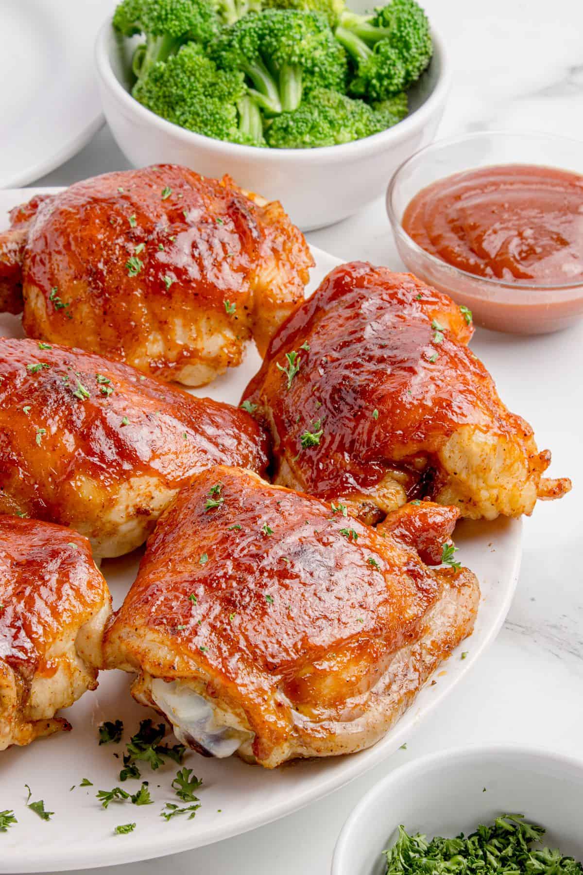 Completed BBQ chicken thighs on a white platter.