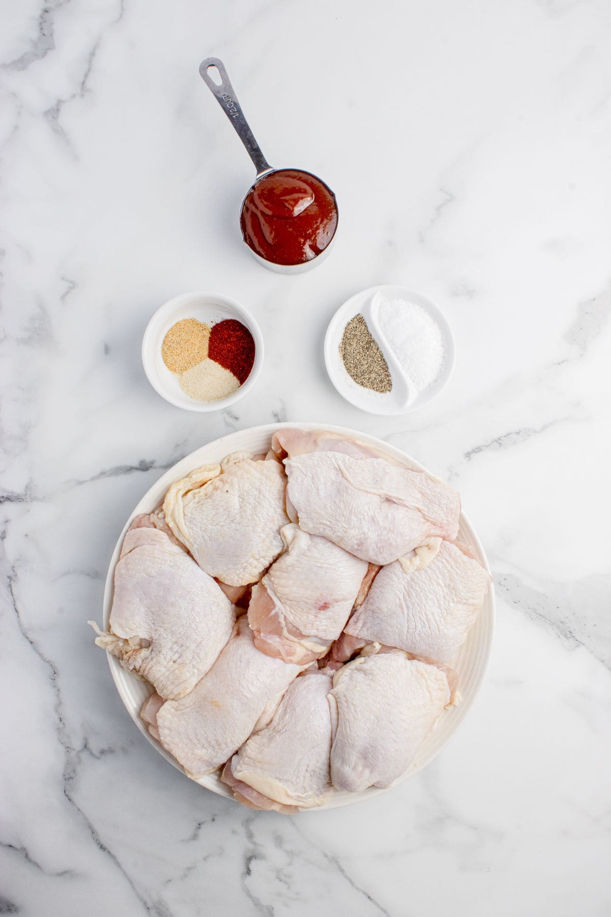 Ingredients for BBQ chicken thighs: chicken thighs, BBQ sauce, salt, black pepper, onion powder, garlic powder, and smoked paprika.