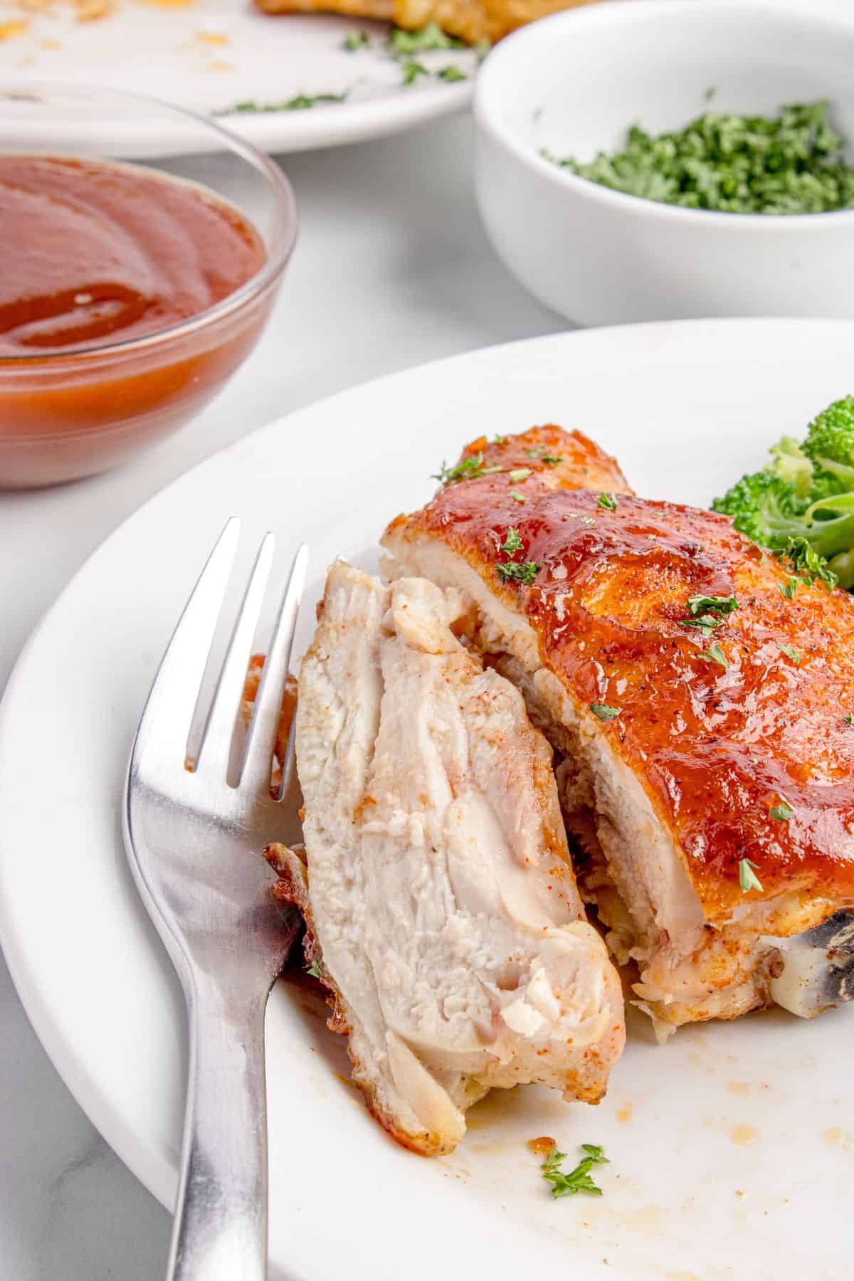A BBQ chicken thigh is sliced in half to show the interior of the chicken.