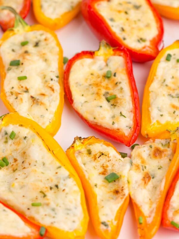 Cream cheese stuffed peppers on a white serving platter.