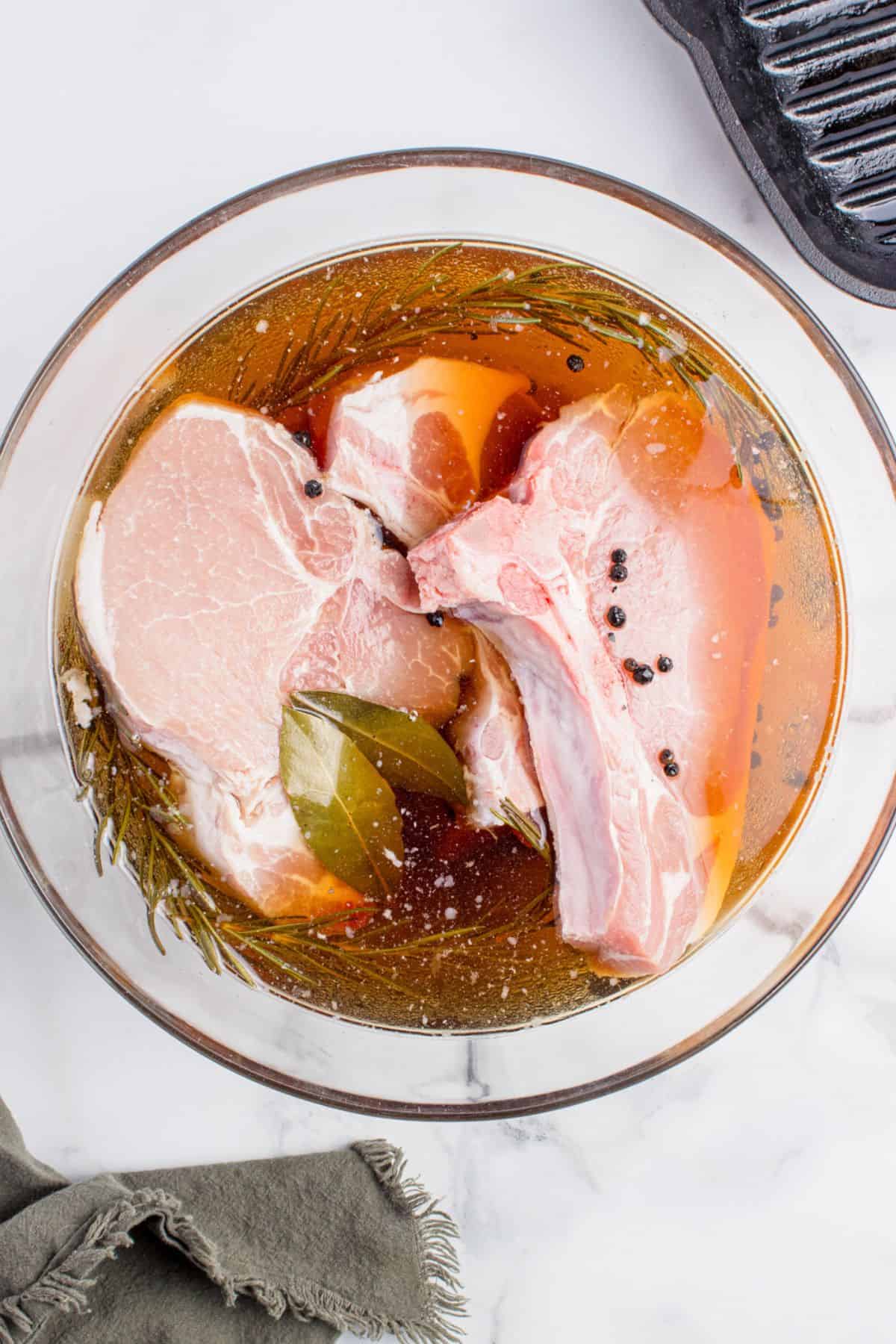 Pork chops in a glass mixing bowl with the cooled brine mixture.