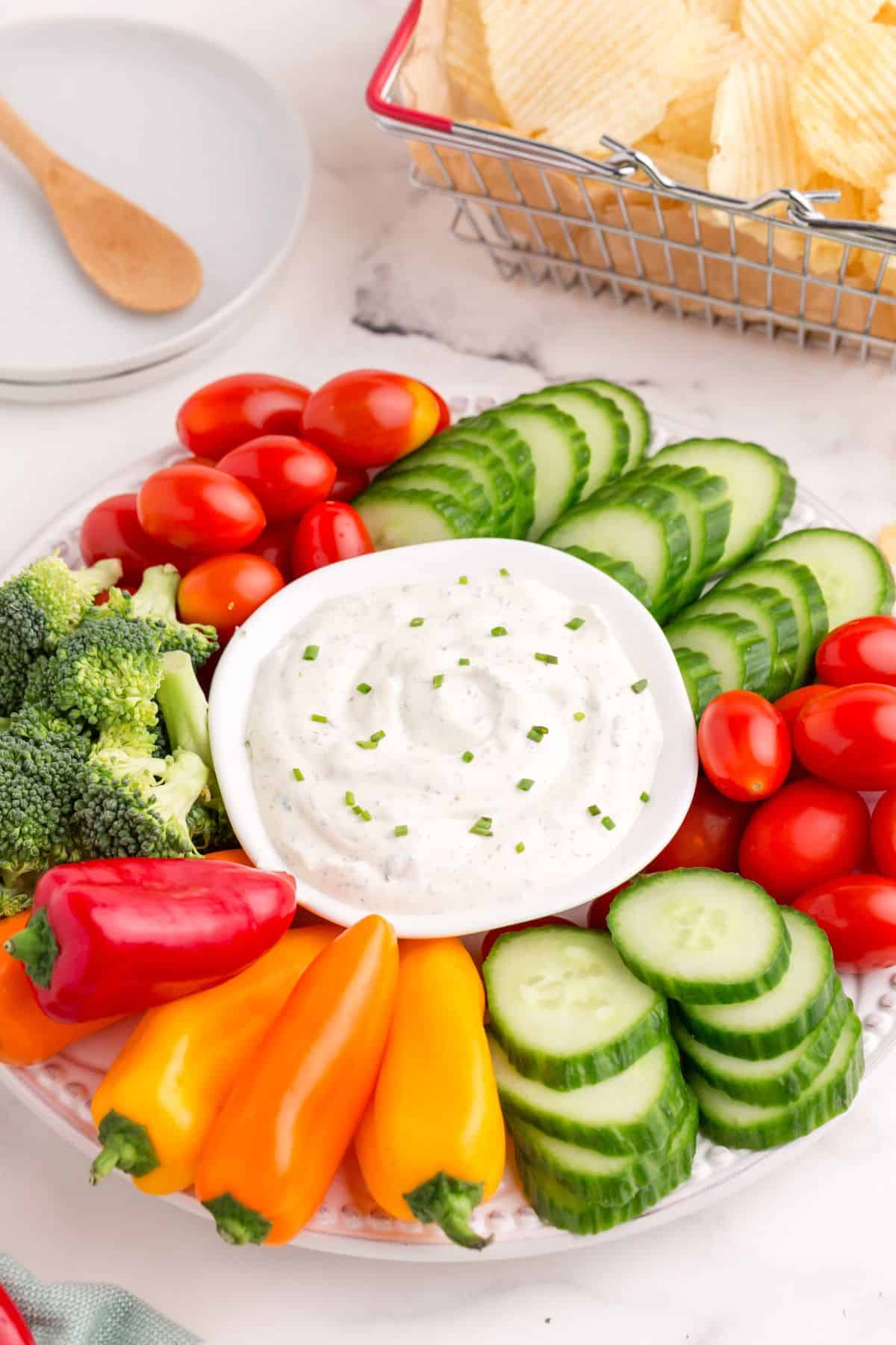 A bowl of ranch dip nestled in the middle of a vegetable platter.