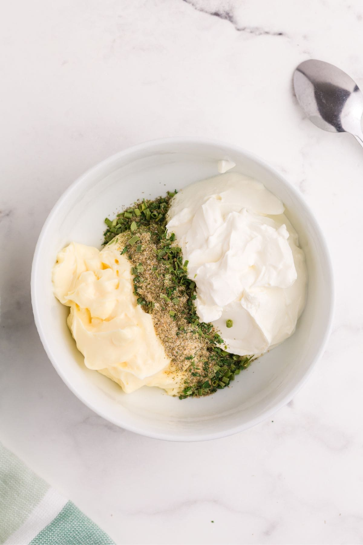 Mayonnaise, sour cream, and ranch spices combined in a bowl to make ranch dip.