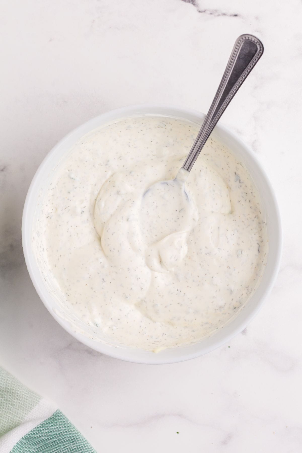 Completed ranch dip in a white bowl with a metal spoon.