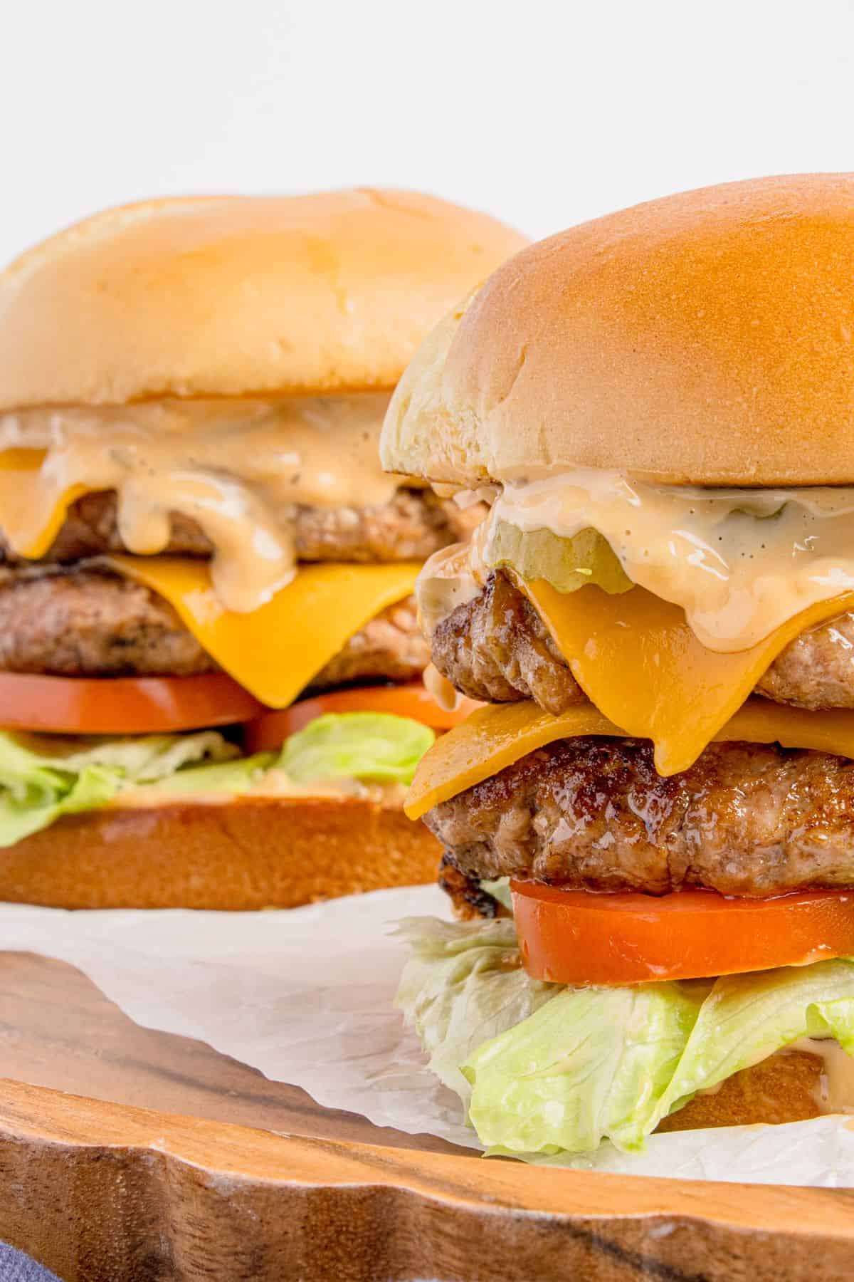 Two smash burgers lined up on a wooden platter.