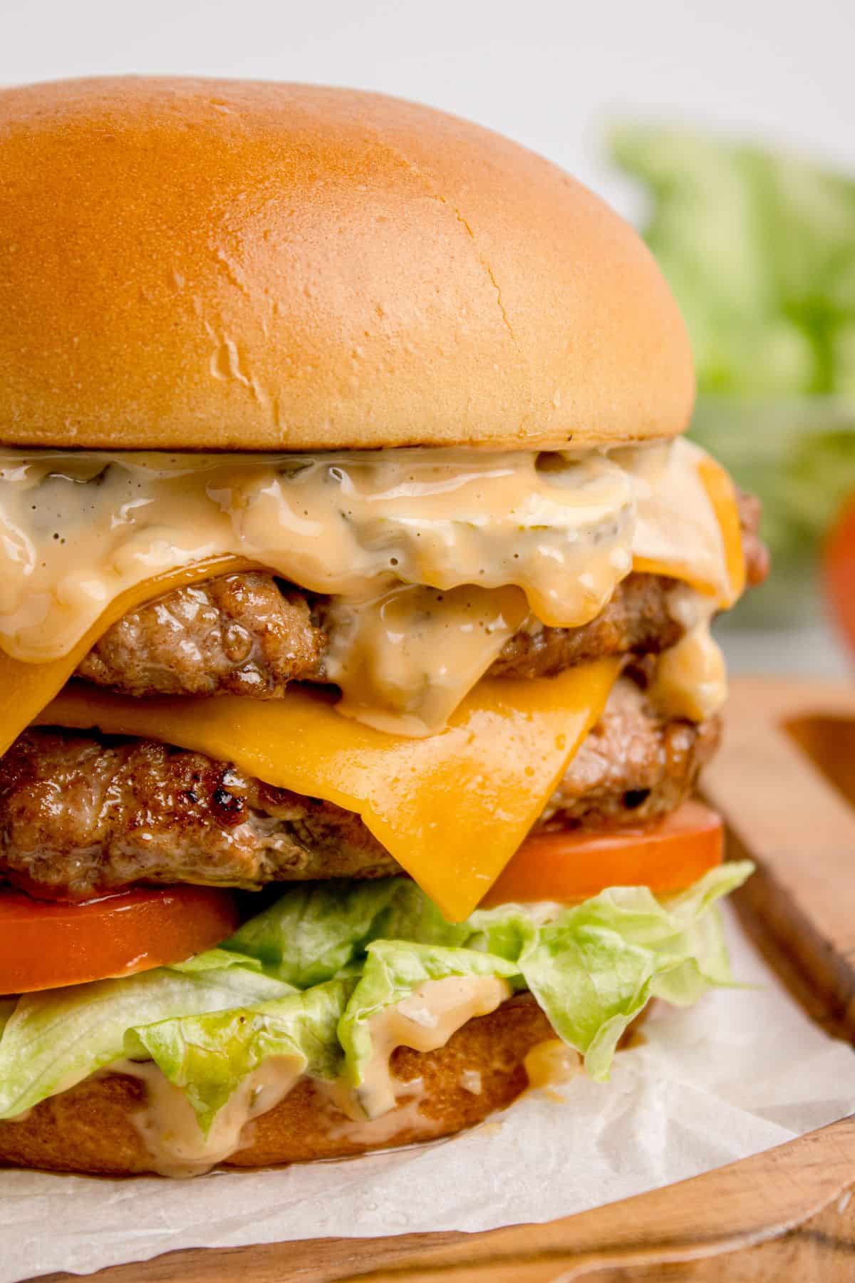 Completed smash burger with two beef patties, smash burger sauce, cheese, tomatoes, and lettuce.