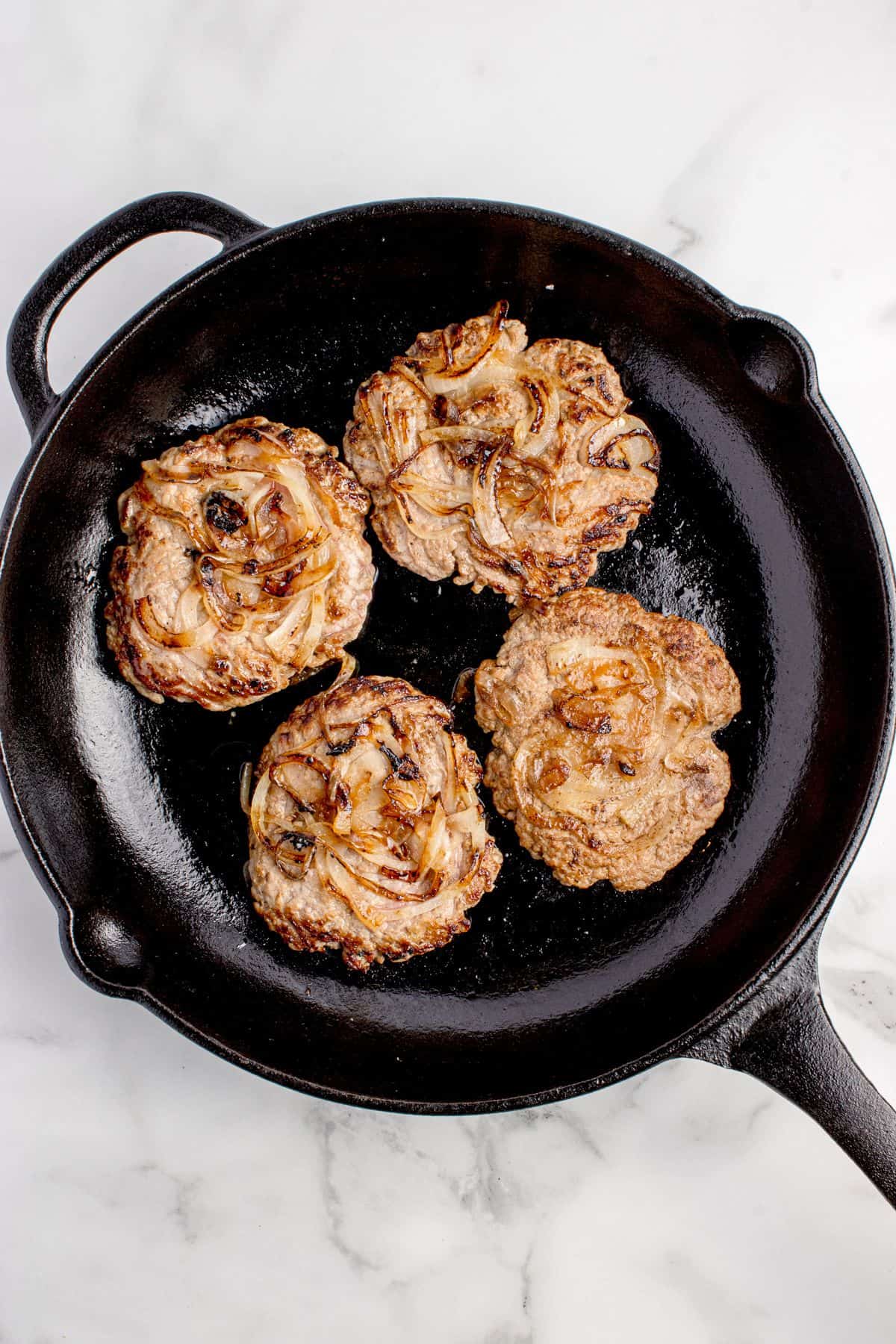 Onions cooking into the ground beef patties.