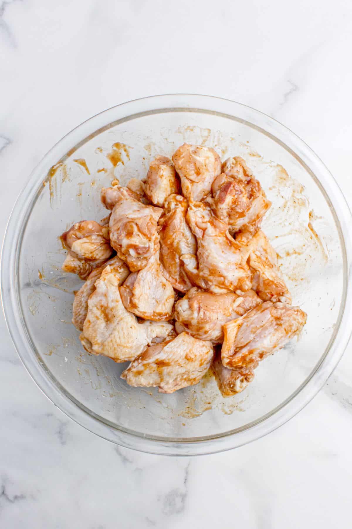 Seasonings and first bit of BBQ sauce on wings in a bowl.