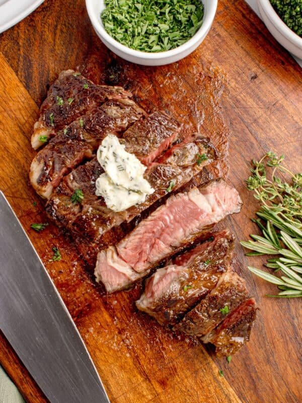 Sliced beef chuck eye steak on a wooden cutting board. One slice is turned sideways to show the interior of the steak.