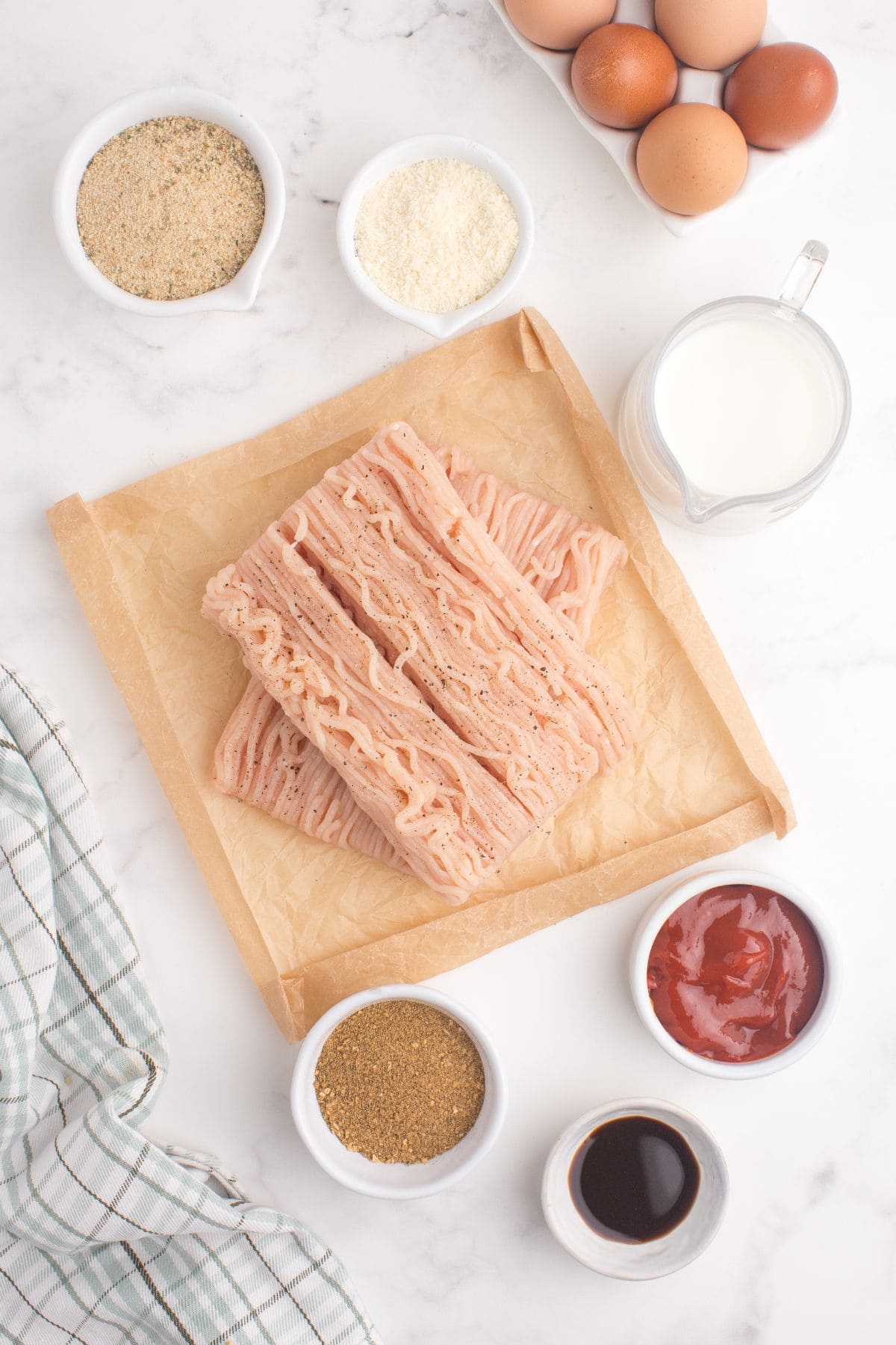 Ingredients for chicken meatloaf: ground chicken, meatloaf seasoning, eggs, grated parmesan, seasoned bread crumbs, milk, ketchup, brown sugar, and worcestershire sauce.