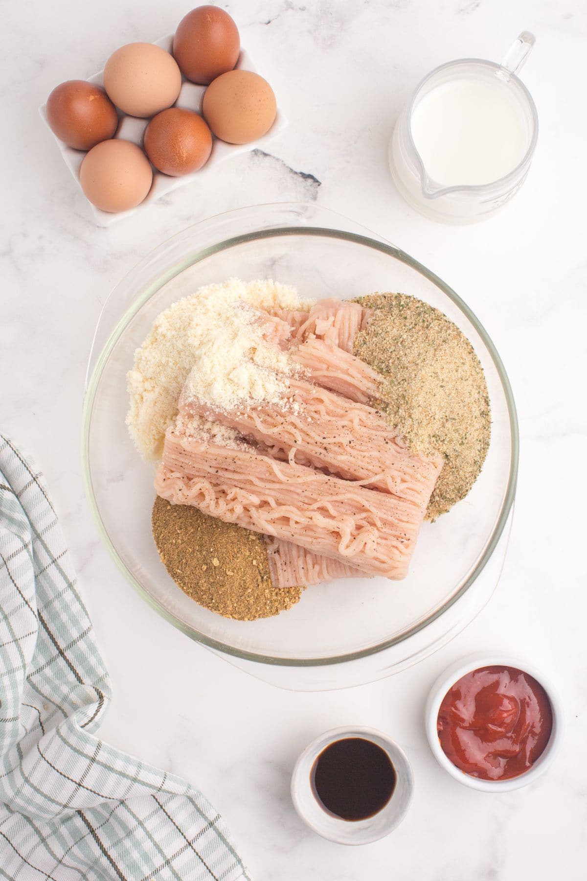 Ingredients for chicken meatloaf are combined in a glass baking dish to make the meatloaf mixture.