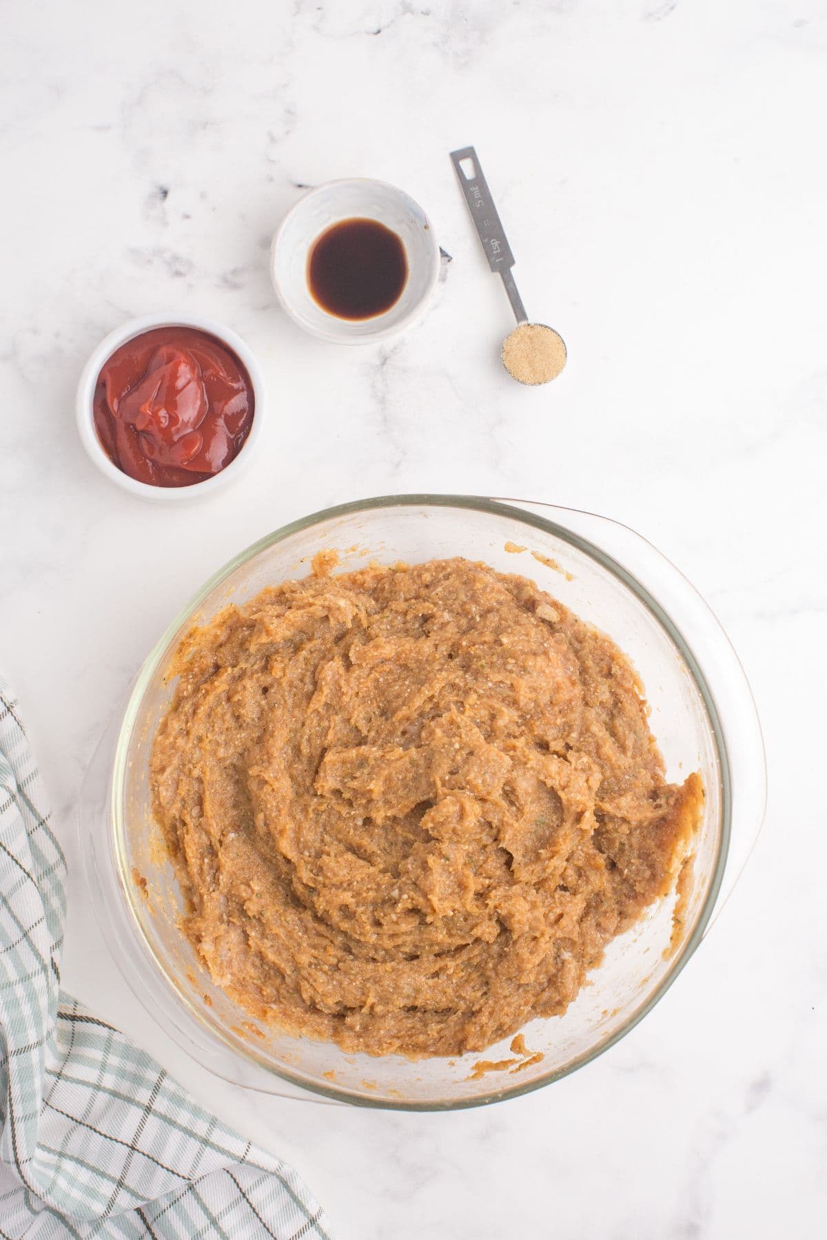 Chicken meatloaf ingredients are combined in a glass mixing bowl.