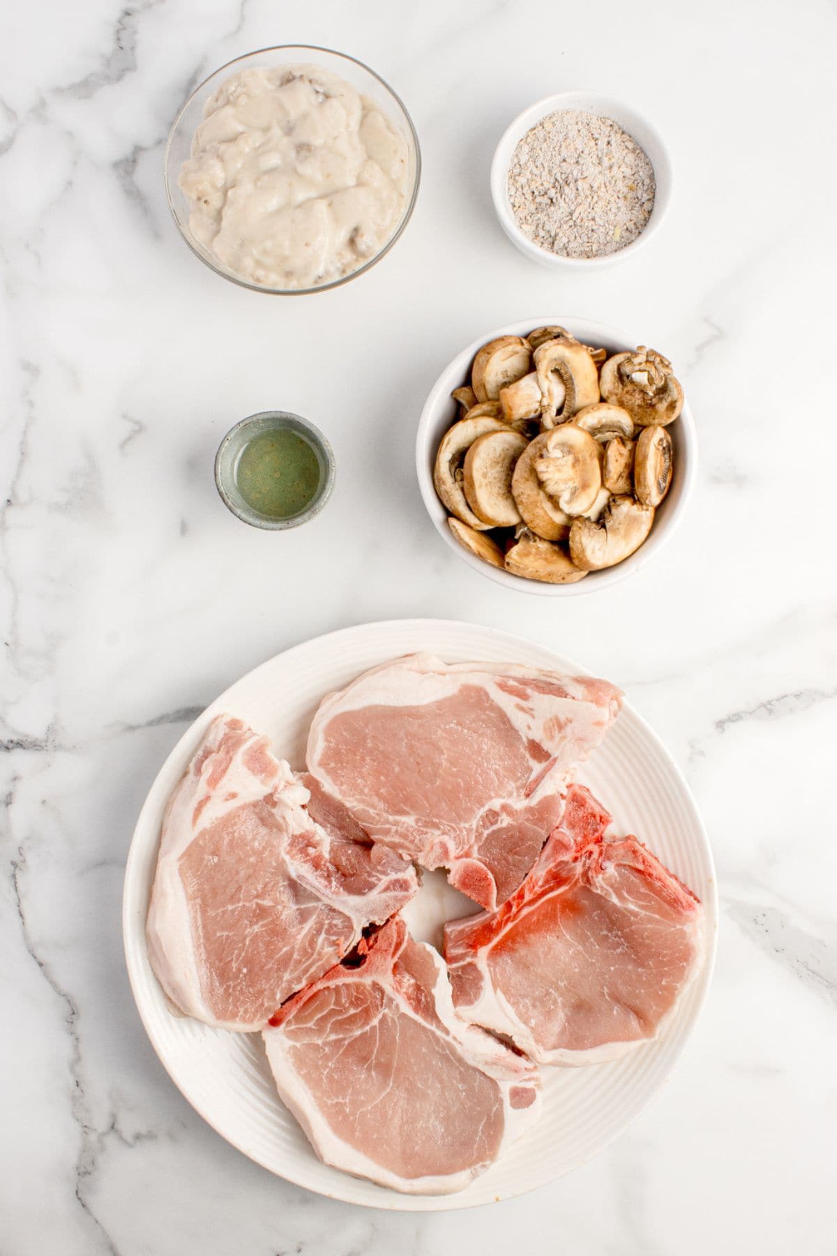 Ingredients for crock pot pork chops with mushroom soup: pork chops, olive oil, cream of mushroom soup, dry onion soup mix, and sliced mushrooms.