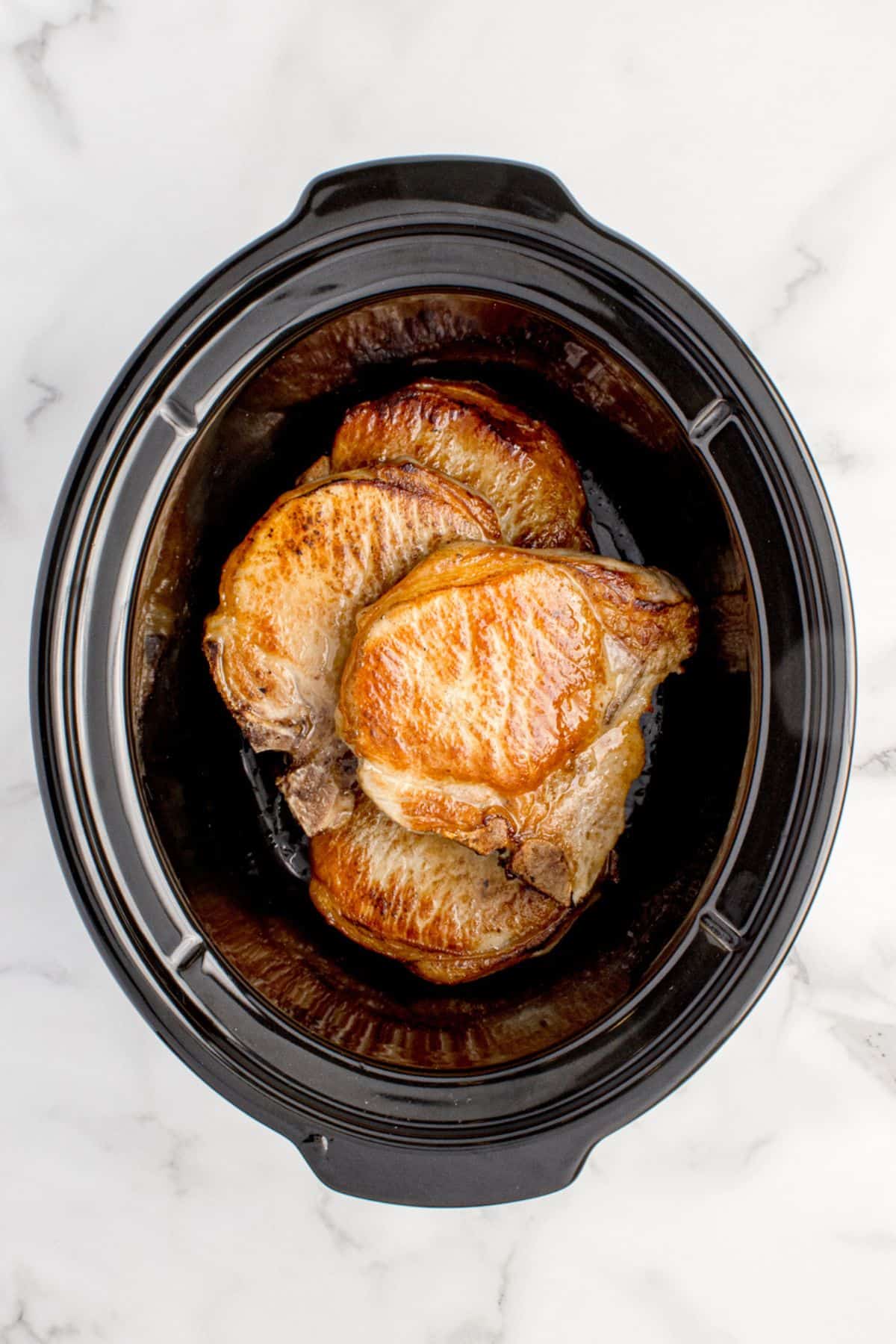 Seared pork chops added to the bottom of the crock pot insert.