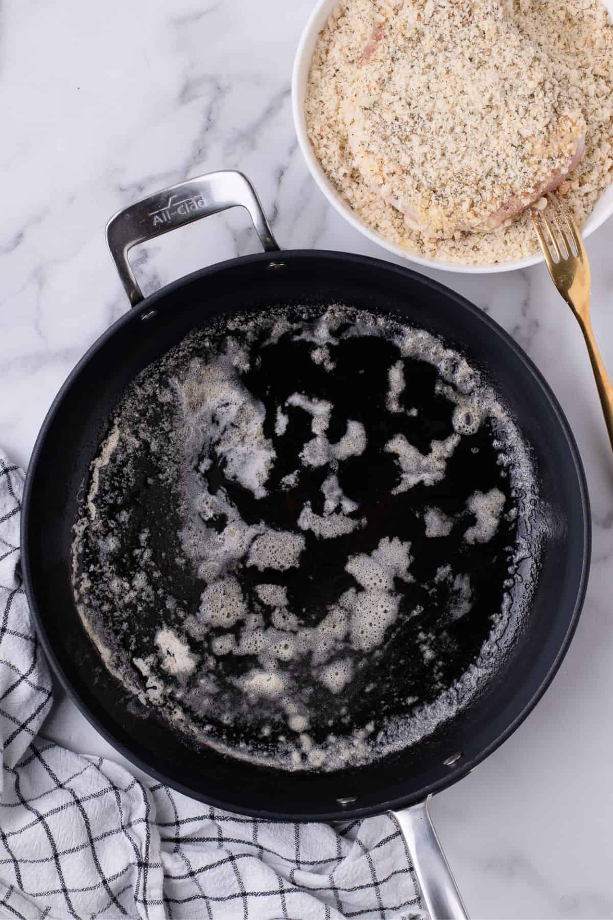 Oil and butter being heated up in an oven safe skillet.