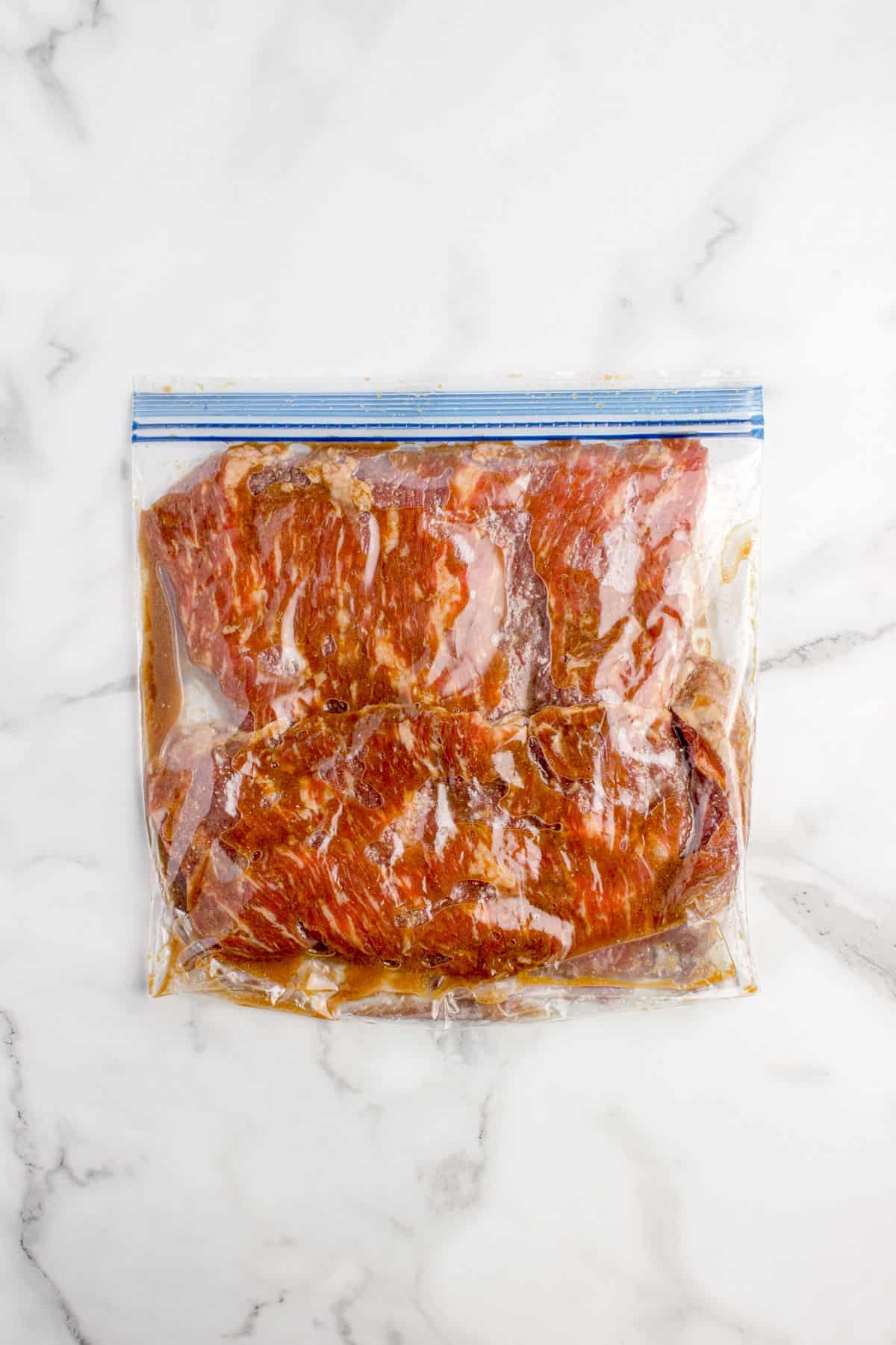 Skirt steak marinating in a plastic zip top bag.