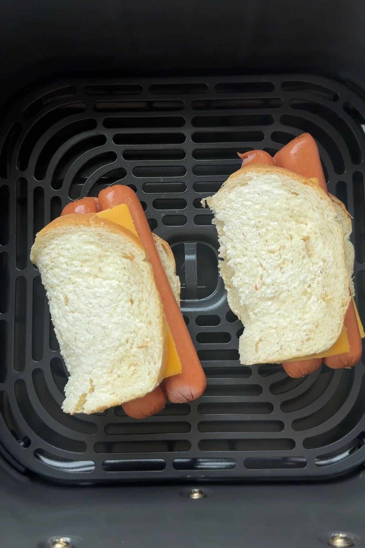 Air fryer hot dog grilled cheese about to be air fried in a basket.