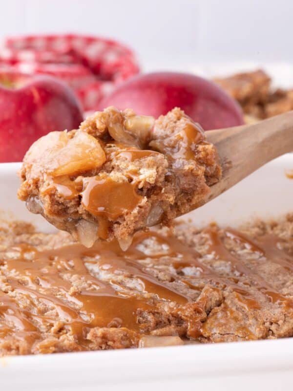 Apple dump cake being picked up with a wooden spoon.