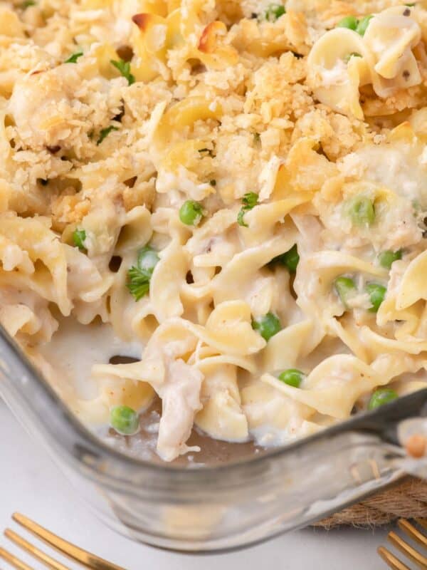 Tuna casserole in a glass baking dish. A serving has been removed from the corner of the baking pan.