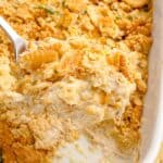 Chicken casserole in a white baking dish. A serving has been removed from the corner of the dish.