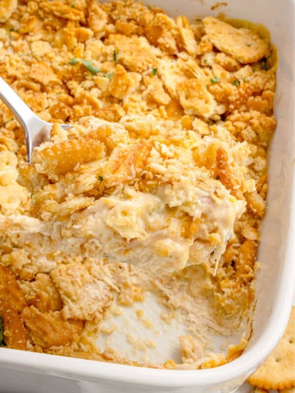 Chicken casserole in a white baking dish. A serving has been removed from the corner of the dish.